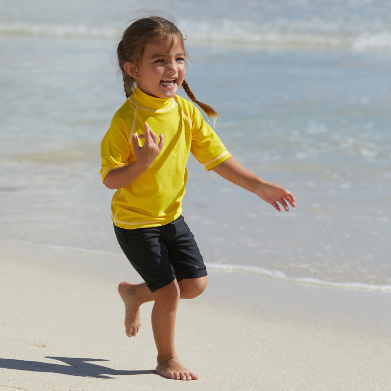 Little girl in UV Skinz's kid's short sleeve swim shirt in cyber yellow|cyber-yellow