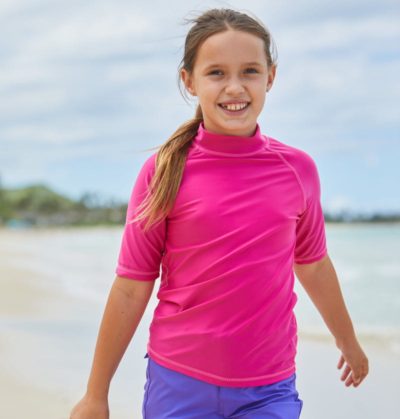 Young girl in UV Skinz's kid's short sleeve swim shirt in hot pink|hot-pink