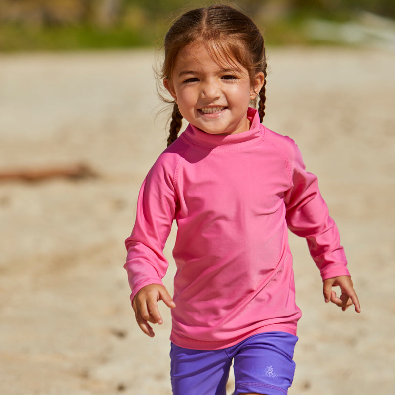Little girl playin on the beach in the kid's long sleeve swim shirt in bubblegum|bubblegum