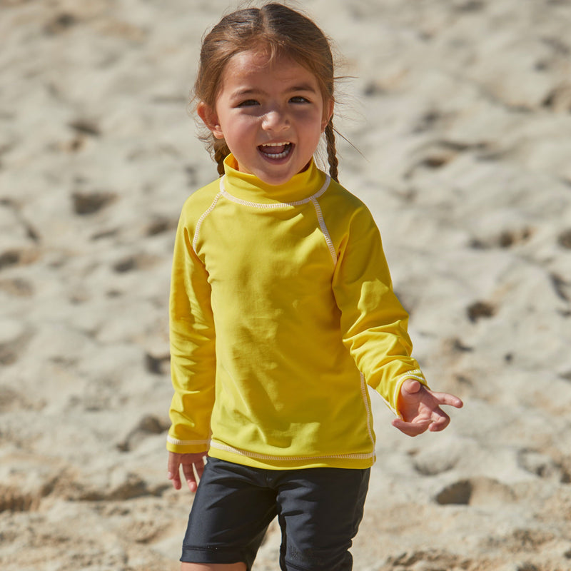 Little girl playing on the beach in kid's long sleeve swim shirt in cyber yellow|cyber-yellow