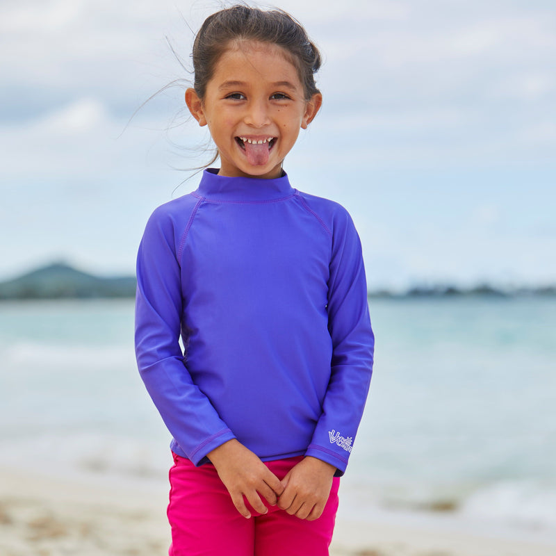 Girl playing on the beach in UV Skinz's kid's long sleeve swim shirt in purple|purple