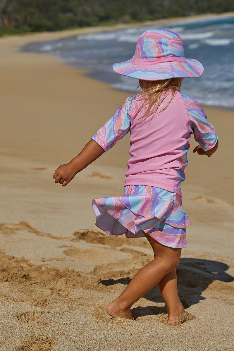 Little girl running on the beach in UV Skinz's girl's short sleeve sunny swim shirt in rollin along|rollin-along