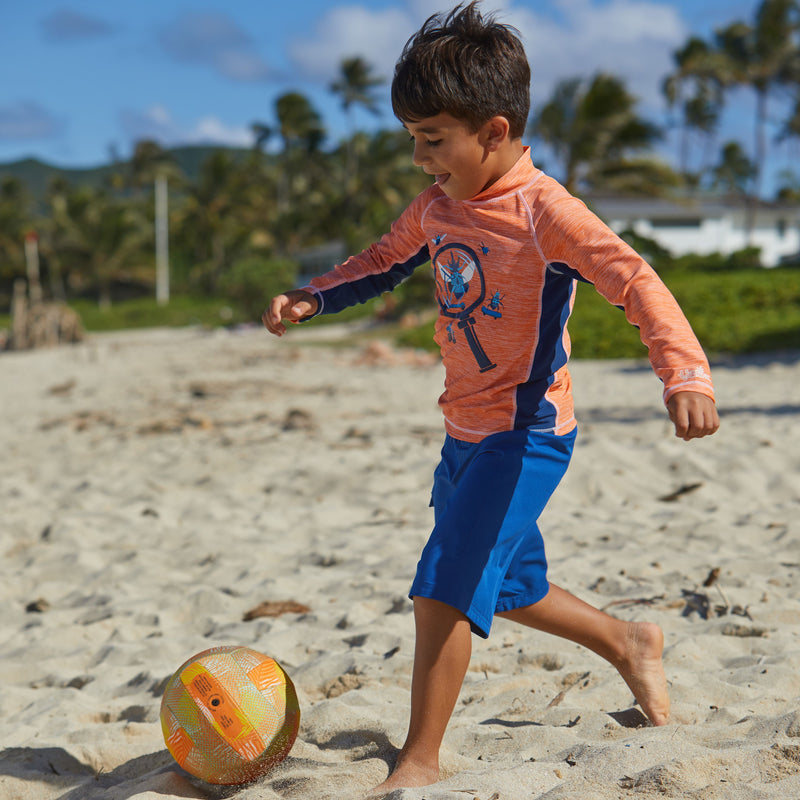 Boy Playing Soccer on the Beach in UV Skinz's Boy's Classic Board Shorts in Navy|navy