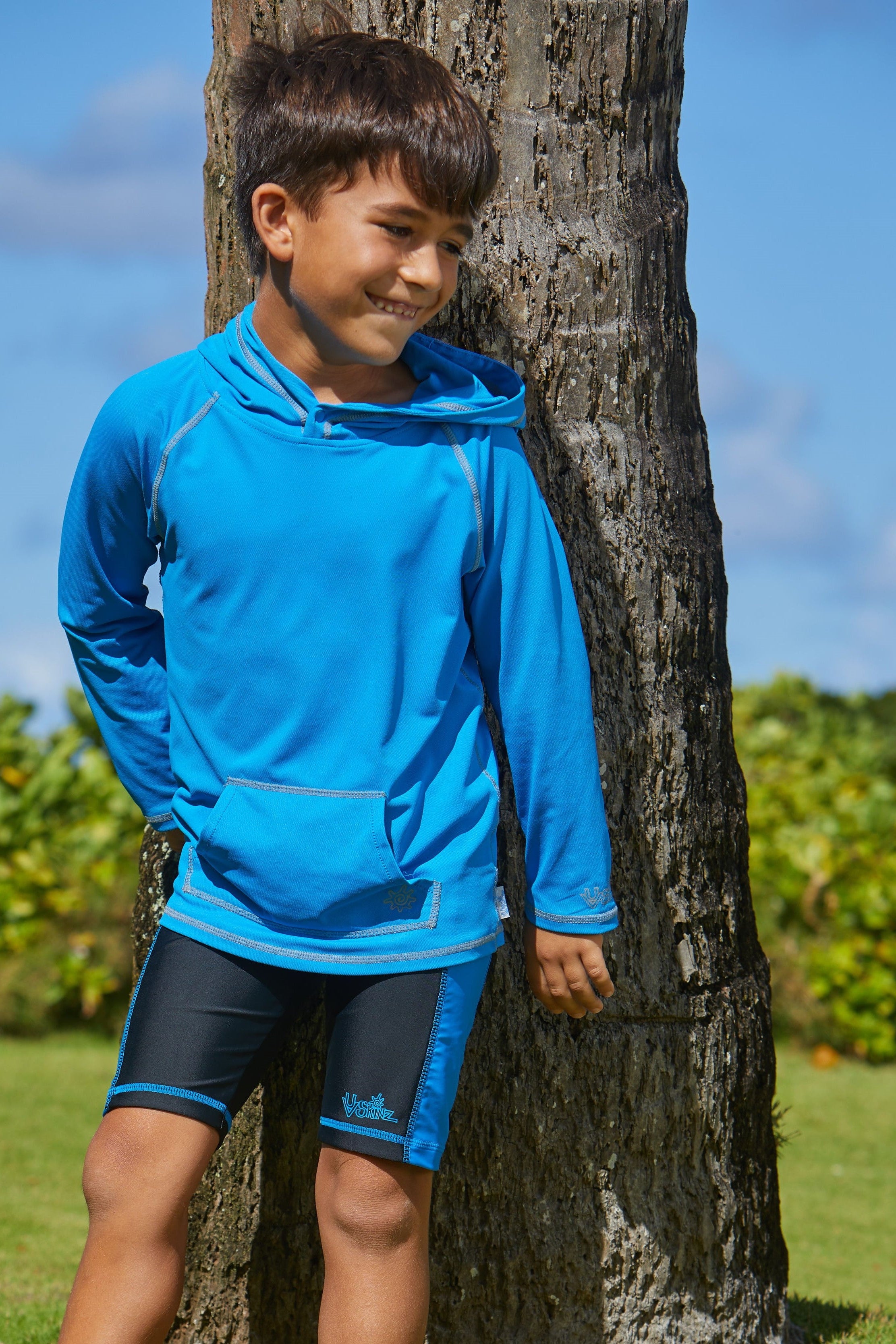 Boy wearing UV Skinz's boy's swim shorts in black royal|black-royal