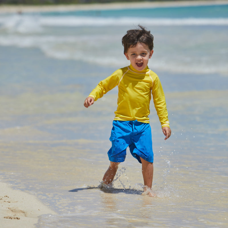 Little boy playing in the ocean in the kid's long sleeve swim shirt in cyber yellow|cyber-yellow