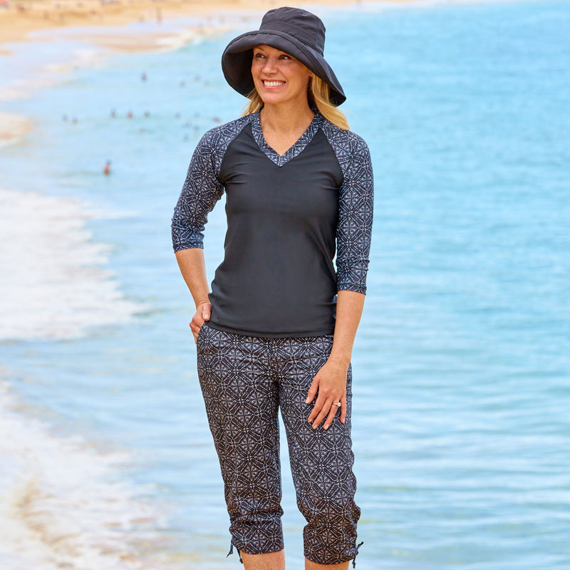 Woman wearing UV Skinz's women's v-neck 3/4 swim shirt in black medallion|black-medallion