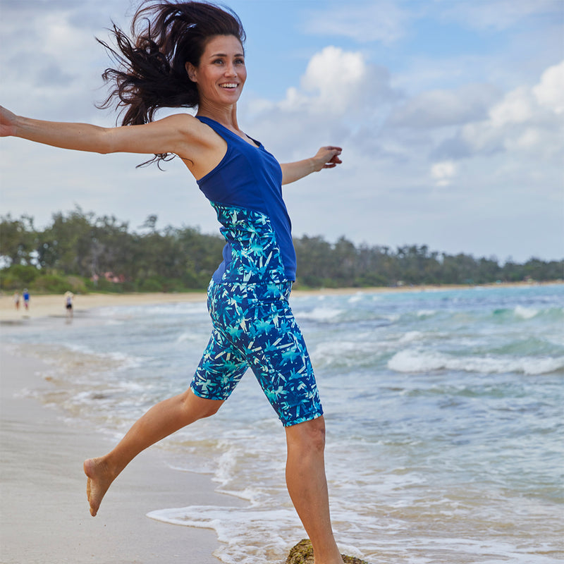 Woman jumping into the ocean in her UV Skinz's active swim jammerz in tie dye burst|tie-dye-burst