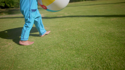 Baby boy playing in UV Skinz's long-sleeve swimsuit with UPF