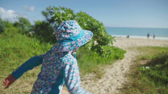 Little girl playing on the beach wearing UV Skinz's girl's swim hat