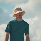 man walking the beach in UV Skinz's men's short sleeve swim shirt in dark teal