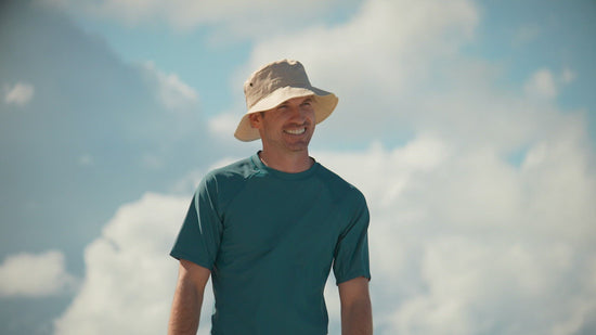 man walking the beach in UV Skinz's men's short sleeve swim shirt in dark teal