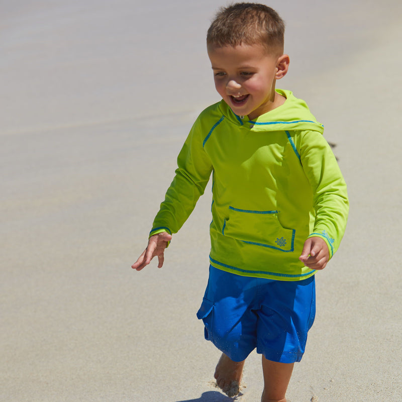 Little boy playing on the beach in UV Skinz's boy's pullover hoodie in lime punch|lime-punch