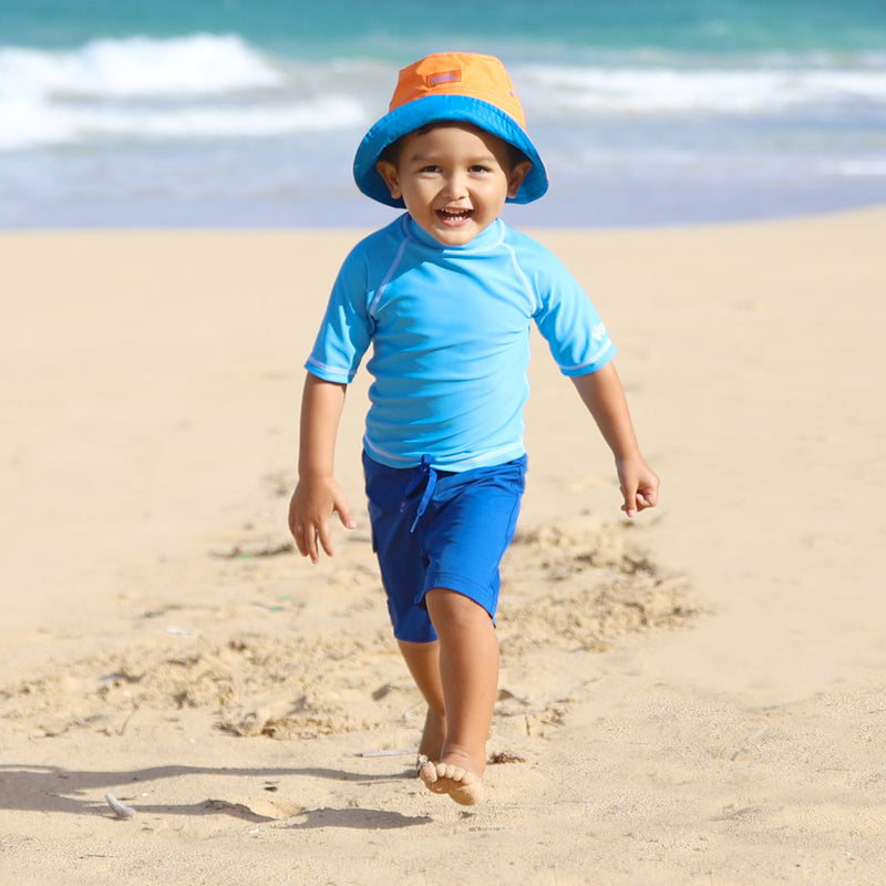Little boy on the beach in kid's short sleeve swim shirt in ocean blue|ocean-blue