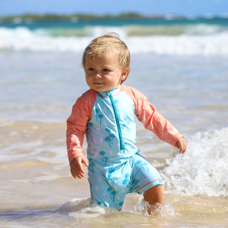 Baby on the beach in UV Skinz's sun protective baby swimsuit|beach-trees