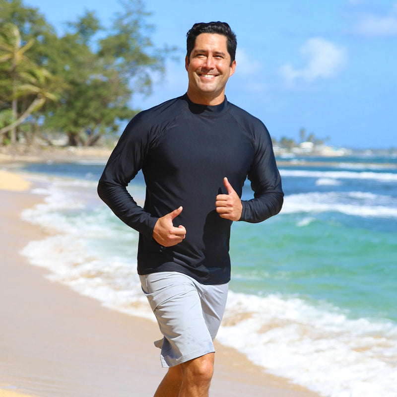 Man running down the beach in UV Skinz's men's long sleeve swim shirt in black|black