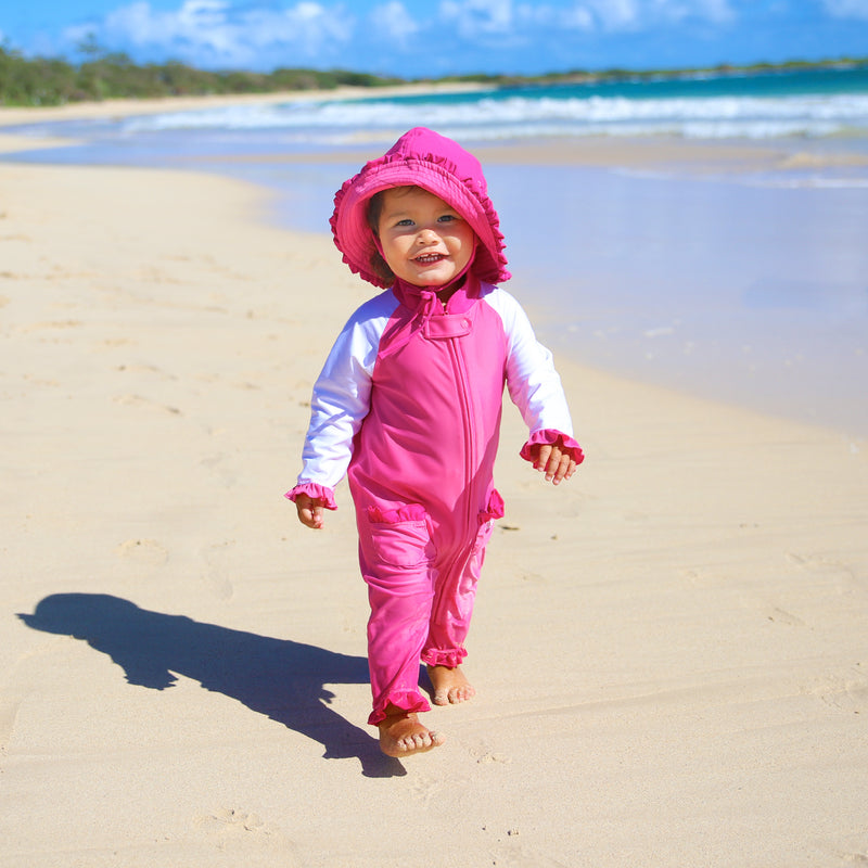 Baby girl on the beach in UV Skinz's baby bucket hat in bubblegum hot pink|bubblegum-hot-pink