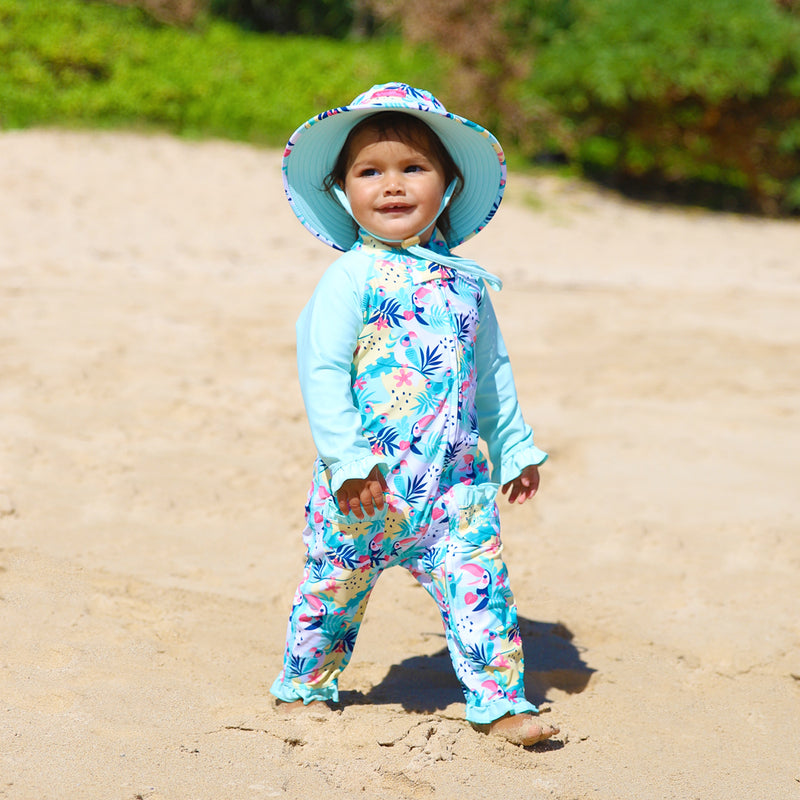 Little baby girl in UV Skinz's baby girls long-sleeve swimsuit in beach glass toucan|beach-glass-toucan