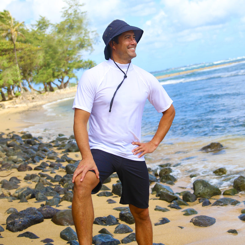 Man on the beach in UV Skinz's men's coastal board shorts in black|black