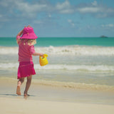 Little girl playing on the beach in UV Skinz's kid's short sleeve swim shirt 