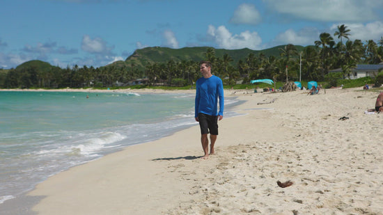 Man walking on the beach in UV Skinz's men's coastal board shorts