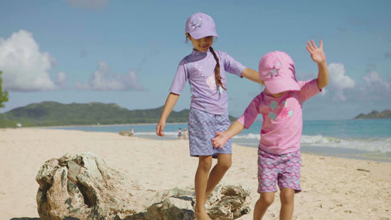 Little girls playing on the beach in UV Skinz's girl's snap back hats