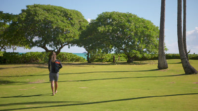 Woman walking on the beach in UV Skinz's long sleeve women's rash guard